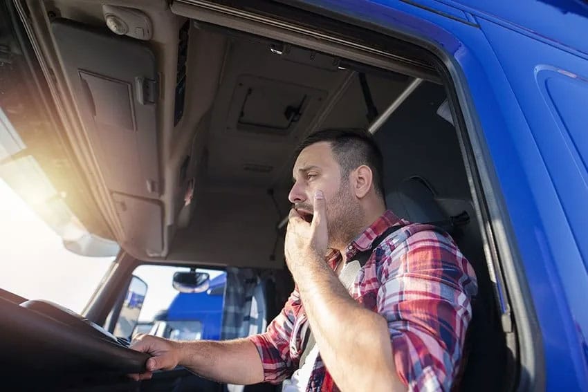 tired truck driver yawns while on the road