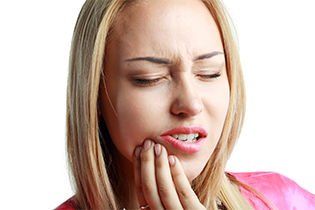 young woman suffering from TMJ pain rubs the side of her mouth