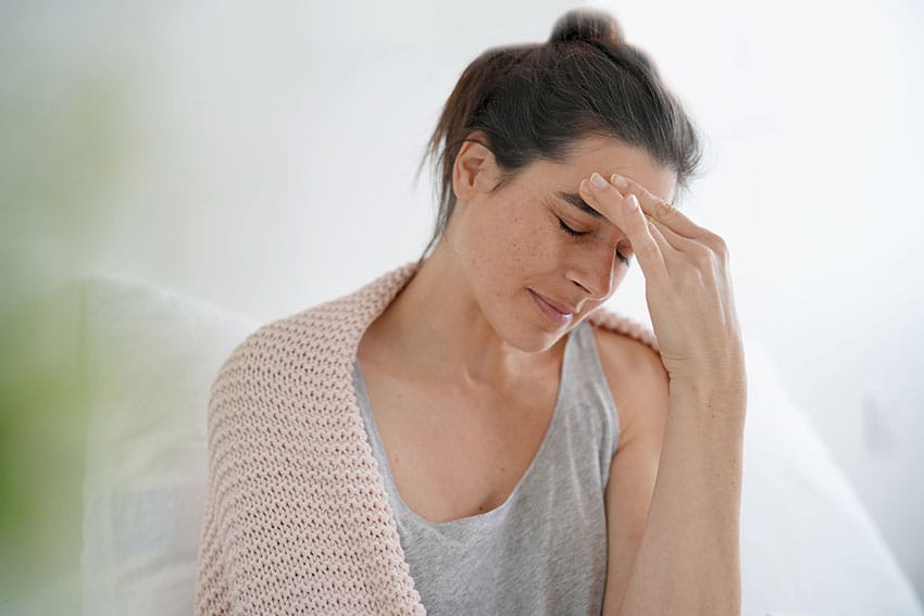 woman sitting with sweater with head pain