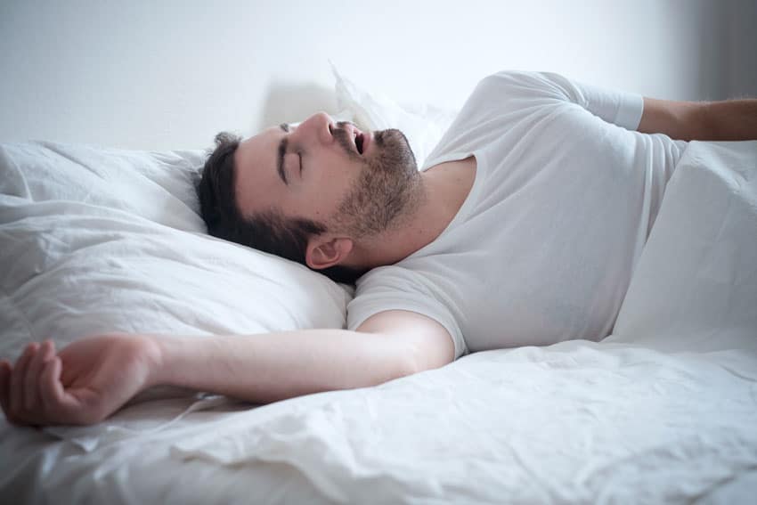 man sleeping in bed with his mouth open