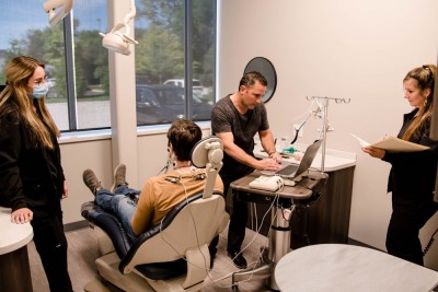 Michigan TMJ dentist reviews a patients pain symptoms with members of his staff looking on in his Michigan office
