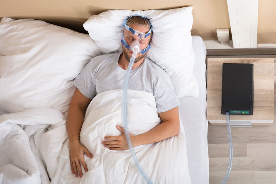 cpap-alternative-detroit Man sleeping with a CPAP machine, illustrating sleep apnea treatment and improved nighttime breathing.