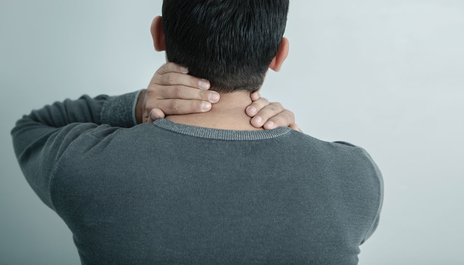 Person holding the back of their neck, illustrating neck pain or stiffness often linked to TMJ disorders.