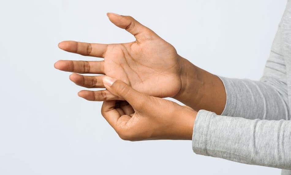 numb-tingle-detroit Person massaging a finger joint, illustrating hand pain, arthritis, or joint discomfort.