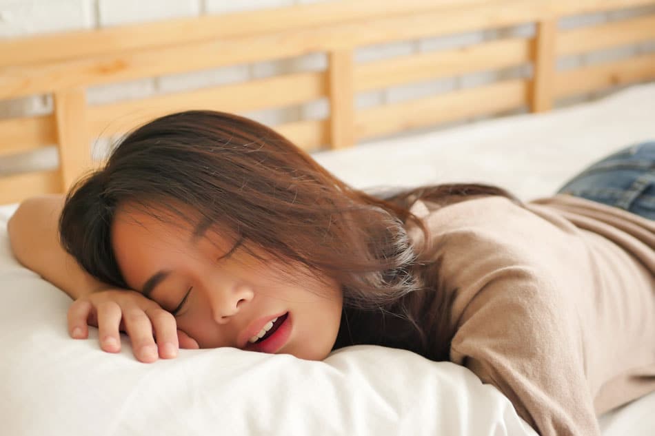 otc-snoring-remedies-detroit Woman sleeping face down with mouth open, illustrating poor sleep quality, snoring, or sleep apnea symptoms.