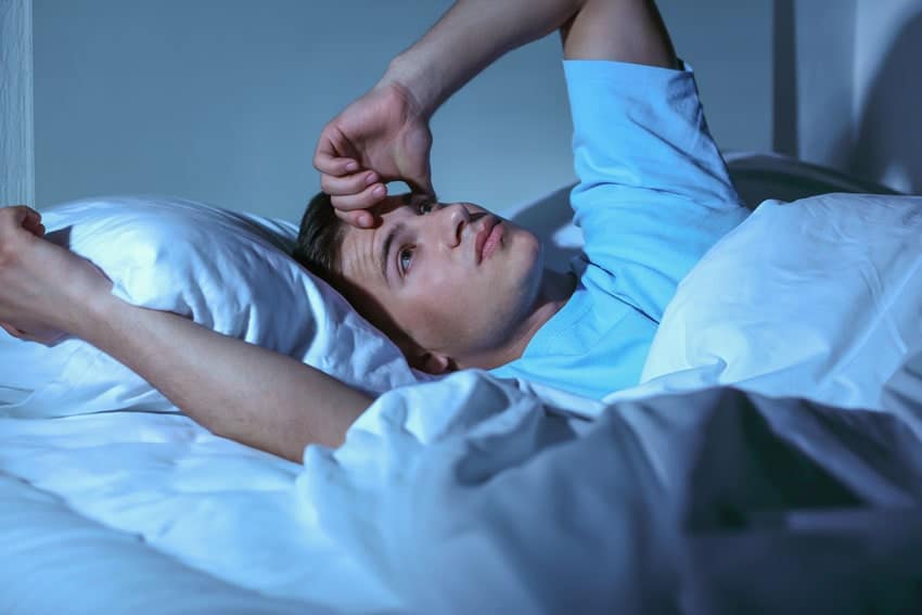 Person lying awake in bed at night, illustrating insomnia, poor sleep quality, or sleep apnea symptoms.