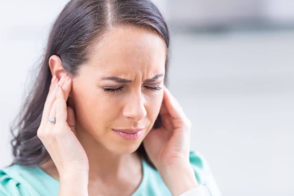 woman with tinnitus holding ears