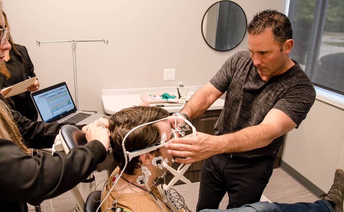 Dr. Haddad positioning jaw-tracking equipment on a patient during a comprehensive TMJ evaluation.