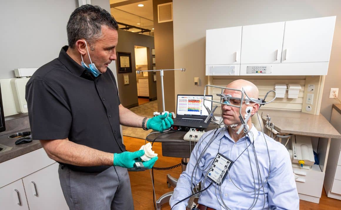 About page content image 2 Dr. Haddad conducting a TMJ evaluation using jaw-tracking technology and diagnostic sensors.