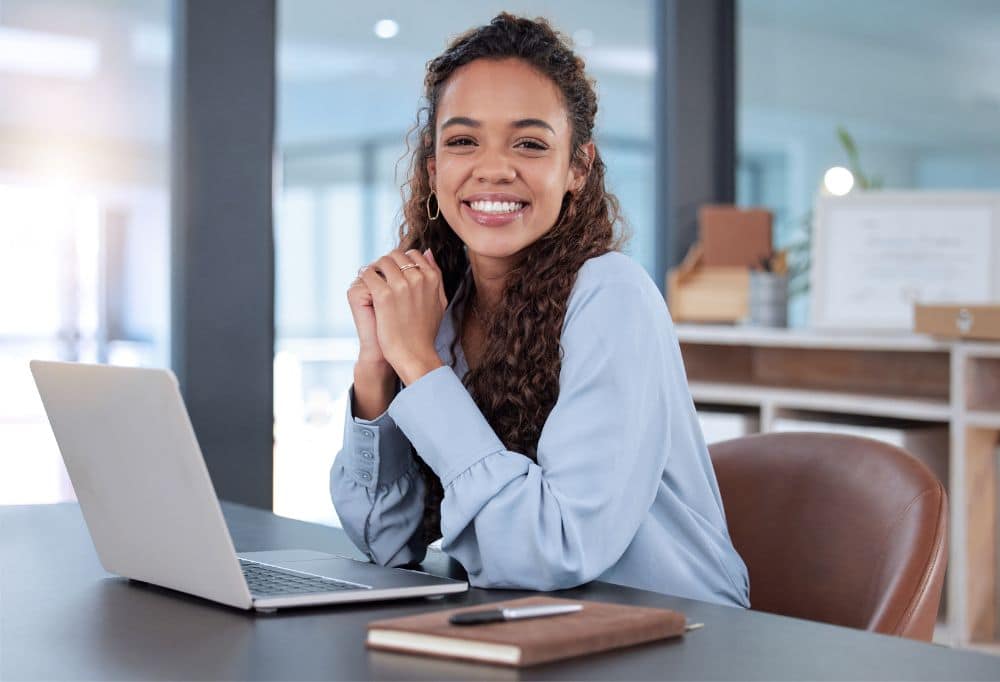Smiling woman working at a laptop, representing productivity, focus, and improved daily well-being.
