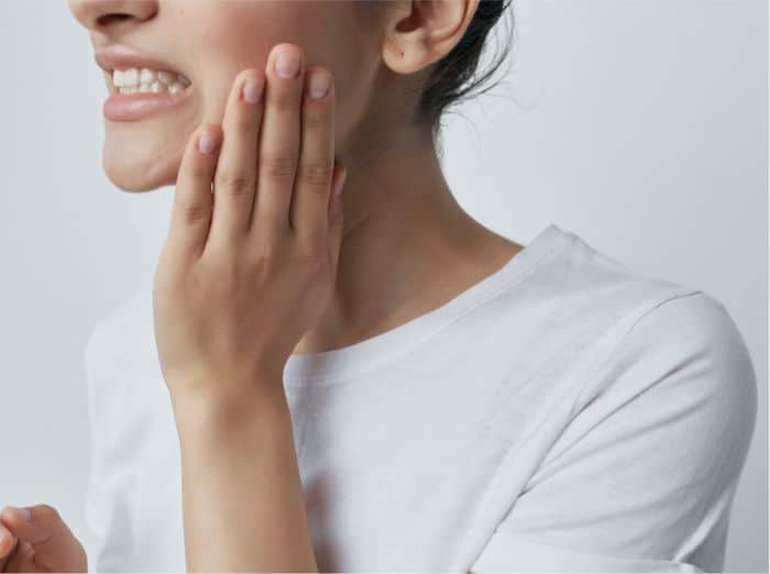 Service page inset image 1 Woman holding her jaw in pain, illustrating TMJ disorder, jaw discomfort, or facial pain symptoms.