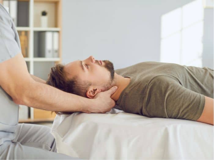 Therapist performing manual neck therapy, illustrating treatment for TMJ-related pain and muscle tension.