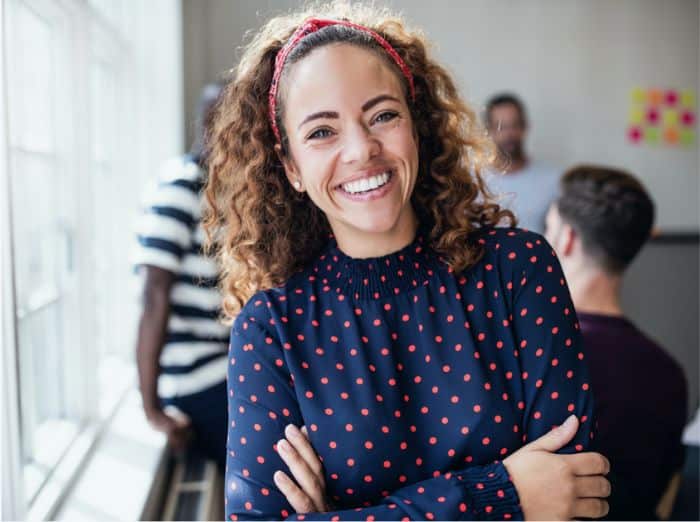 Smiling woman at work, conveying confidence, well-being, and improved quality of life.