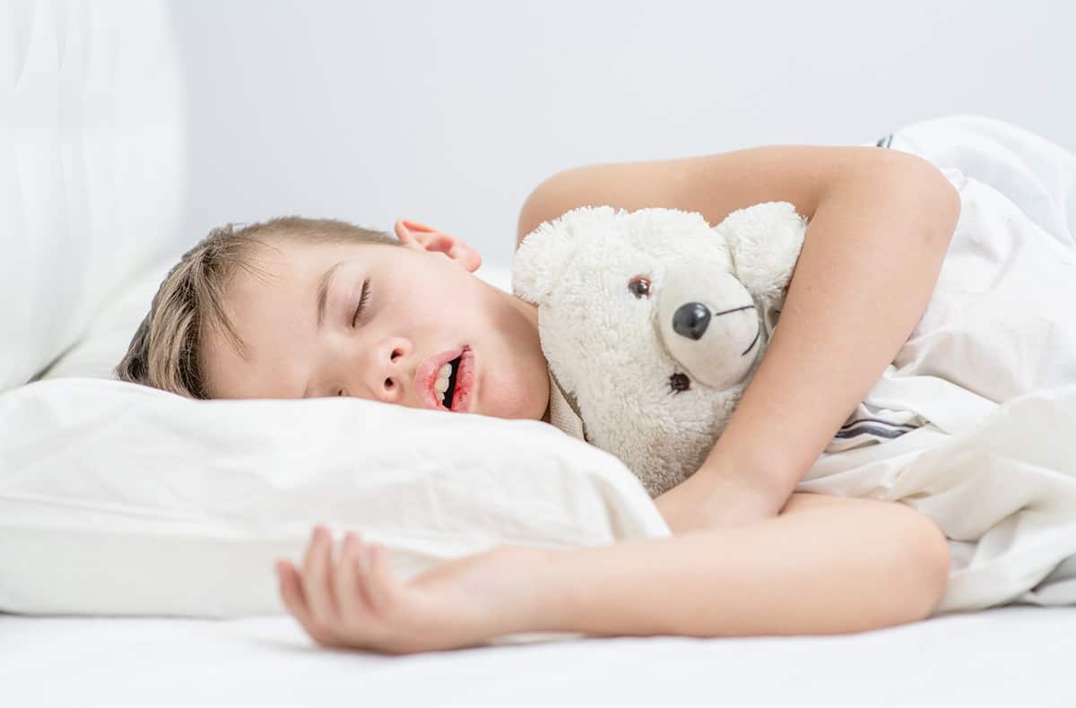 Child snoring Sleeping child cuddles a teddy bear in bed, conveying comfort, security, and restful sleep.