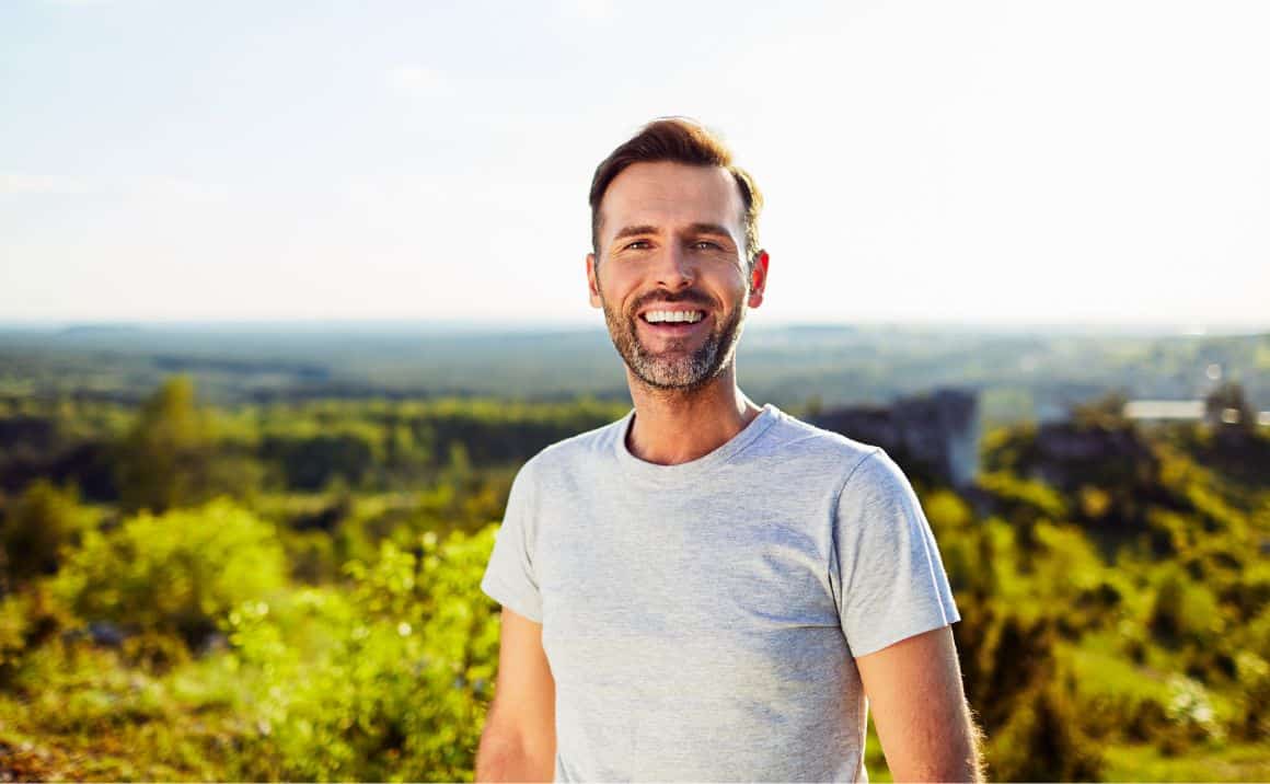 Smiling man outdoors, conveying improved energy, vitality, and quality of life after treatment.
